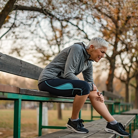 Woman With A Knee Injury Sitting On A Bench